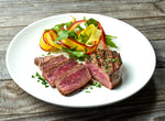 Zoomed out picture of a Ostrich Steak Fan Filet on a plate with a side of rainbow carrots