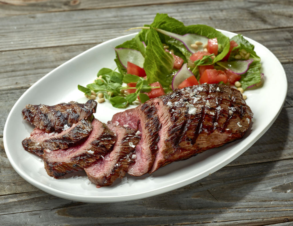 Beautifully prepared Ostrich Steak Inside Strip Filet seasoned with salt next to a green salad