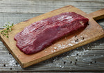 A raw Ostrich Steak Inside Strip Filet  being prepared on a cutting board.