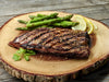 Grilled and seasoned ostrich steak outside strip filet grilled and seasoned presented on a wood round