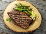 top view of a cooked and seasoned ostrich steak outside strip filet next to asparagus