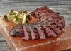 a grilled Ostrich Steak Inside Filet cut that has been sliced and prepared on a salt block alongside mushrooms