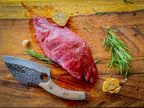 An uncooked ostrich steak outside filet being prepared to be cooked next to a butcher's knife
